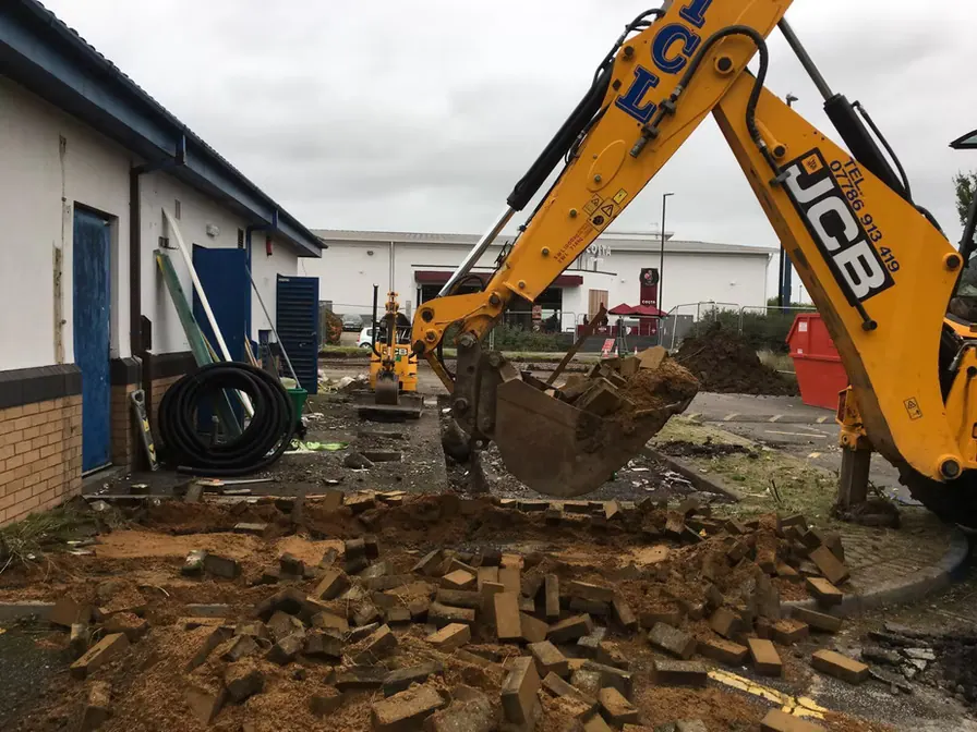 Excavator breaking out an old surface